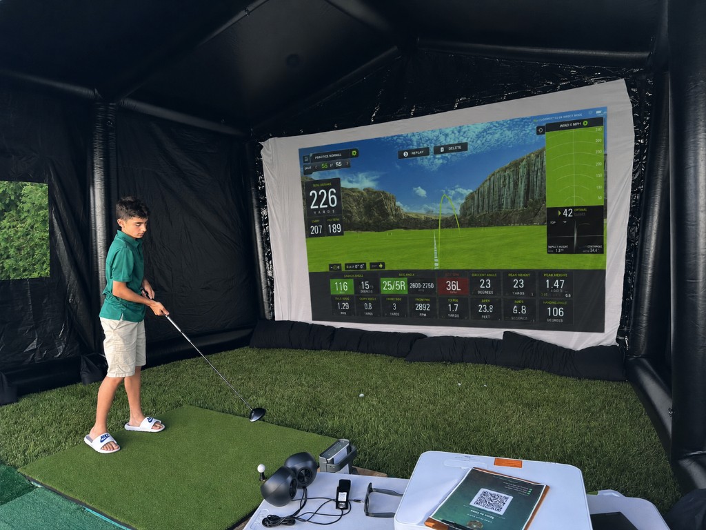 Young golfer hitting a drive into the simulator screen showing a 226-yard shot.